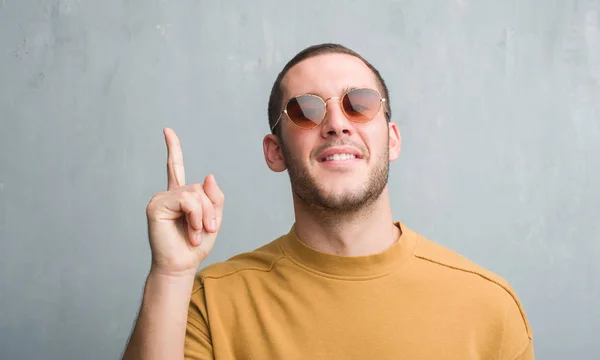 Joven Caucásico Hombre Sobre Gris Grunge Pared Usando Gafas Sol — Foto de Stock