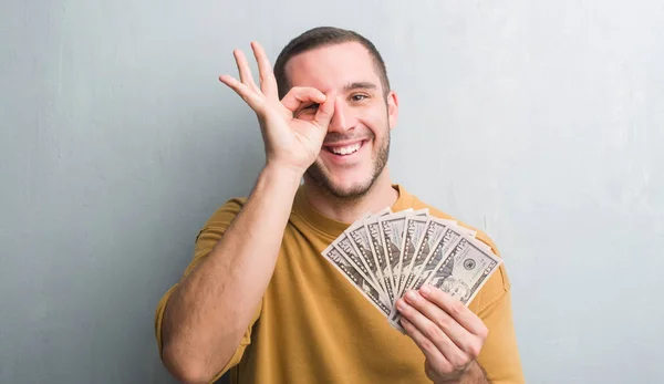 Homem Caucasiano Jovem Sobre Parede Grunge Cinza Segurando Dólares Com — Fotografia de Stock