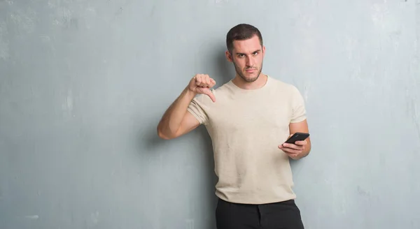Gri Grunge Genç Beyaz Adam Kızgın Yüz Ile Smartphone Kullanarak — Stok fotoğraf