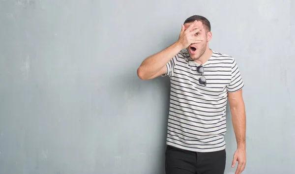 Young Caucasian Man Grey Grunge Wall Peeking Shock Covering Face — Stock Photo, Image