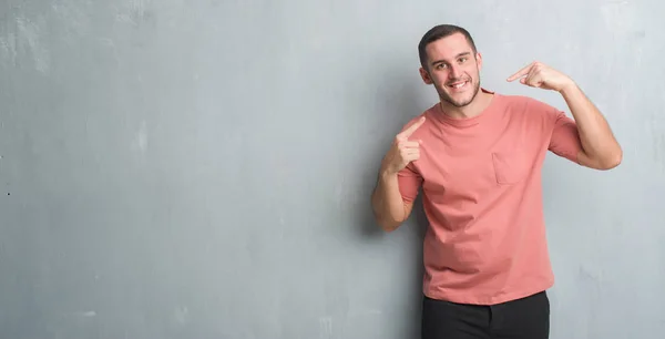 Joven Hombre Caucásico Sobre Gris Pared Grunge Sonriendo Confiado Mostrando —  Fotos de Stock