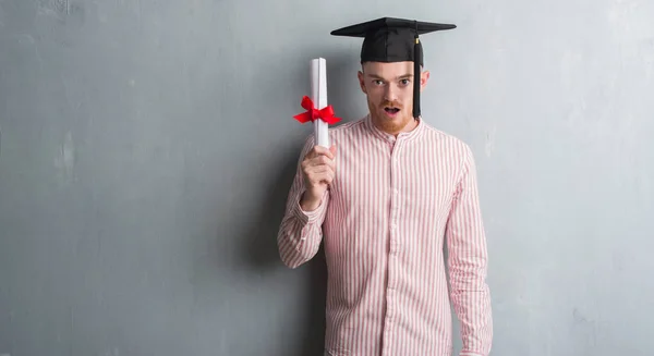 Unga Rödhårig Man Över Grå Grunge Vägg Bär Graduate Cap — Stockfoto