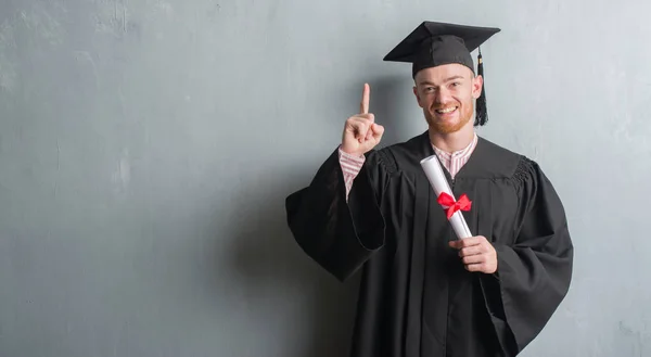 Jovem Ruivo Sobre Parede Grunge Cinza Vestindo Graduado Uniforme Segurando — Fotografia de Stock