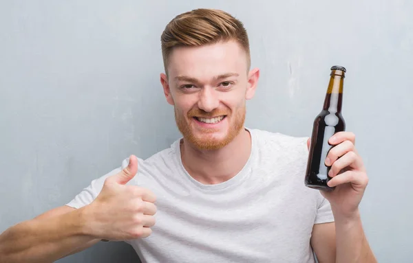 Young Redhead Man Grey Grunge Wall Drinking Beer Bottle Happy — Stock Photo, Image