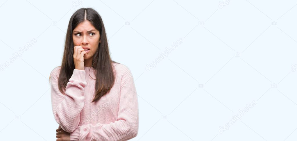 Young beautiful hispanic woman wearing a sweater looking stressed and nervous with hands on mouth biting nails. Anxiety problem.