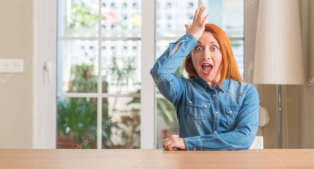 Redhead woman at home surprised with hand on head for mistake, remember error. Forgot, bad memory concept.