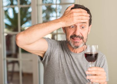 Orta yaş bir kadeh şarap içmek adam vurguladı kafasına, utanç ve sürpriz ile şok el ile karşı karşıya, öfkeli ve sinirli. Korku ve hata için üzgün.