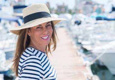 Marina ile mutlu yüz ayakta duran ve diş gösterilen kendine güvenen bir gülümseme ile gülümseyen güzel orta yaş kadın