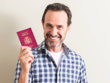 Komuta sizde ayakta ve diş gösterilen kendine güvenen bir gülümsemeyle gülümseyerek mutlu bir yüz ile İspanyol pasaportu holding