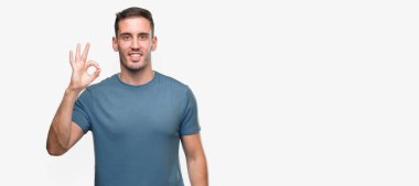El ve parmak ile ok işareti yapıyor olumlu gülümseyen yakışıklı genç casual adam. Başarılı ifade.