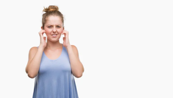 若いブロンドの女性は 大声で音楽の音の腹が立つ式の指を使って耳をカバーします 聴覚障害者の概念 — ストック写真