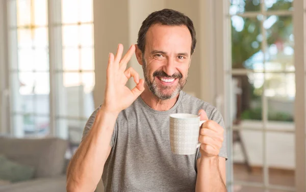 中年男子喝咖啡在杯子做 标志用手指 优秀标志 — 图库照片