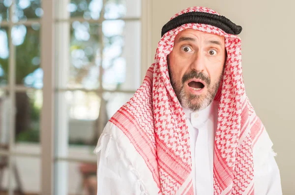 Middle age arabian man at home scared in shock with a surprise face, afraid and excited with fear expression