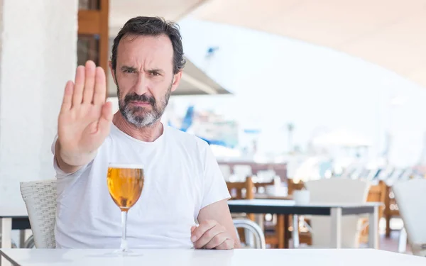 英俊的老人喝啤酒在餐馆用张开的手做停止标志以严肃和自信的表示 防御手势 — 图库照片