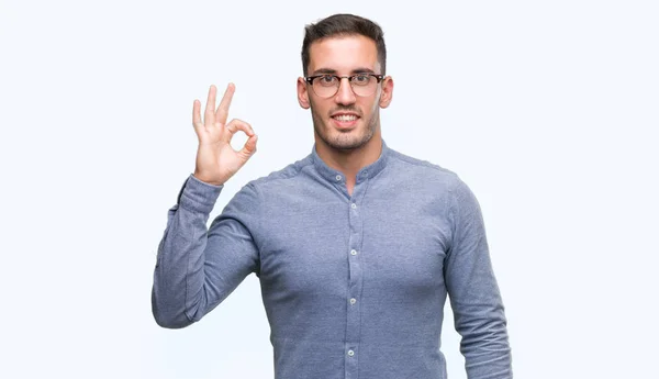 ハンサムな若いエレガントな男は眼鏡を手と指で サインをしている肯定的な笑みを浮かべてします 成功した式 — ストック写真