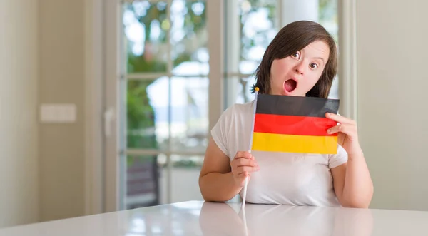 唐氏综合症妇女在家里拿着国旗的德国吓坏了惊讶的脸 害怕和激动与恐惧的表情 — 图库照片