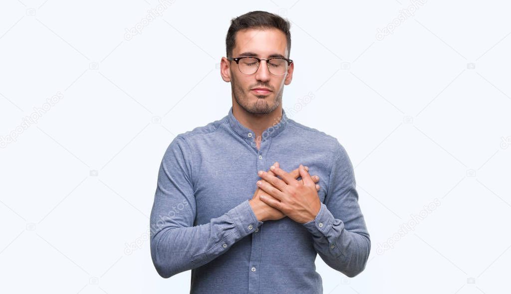 Handsome young elegant man wearing glasses smiling with hands on chest with closed eyes and grateful gesture on face. Health concept.