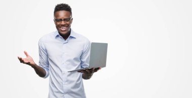 Young african american businessman using computer laptop very happy and excited, winner expression celebrating victory screaming with big smile and raised hands clipart
