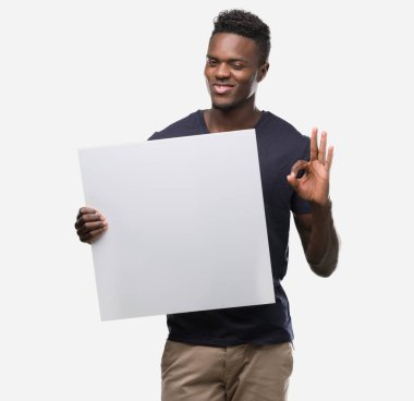 Parmak, mükemmel sembolü ile ok işareti yapıyor bir afiş tutan genç Afro-Amerikan adam