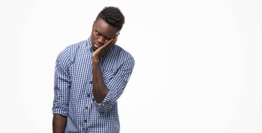 Mavi gömlek düşünme seyir giyen genç Afro-Amerikan adam yorgun ve sıkılmış çapraz silah depresyon sorunları ile.