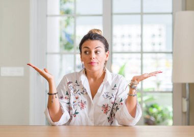 Genç kadın ev clueless ve şaşkın bir ifadeyle kollar ve eller kaldırdı. Şüphe kavramı.