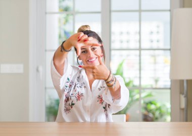 Elleri ile ev gülümseyen yapım çerçeve ve parmakları ile mutlu yüz genç kadın. Yaratıcılık ve Fotoğrafçılık kavramı.