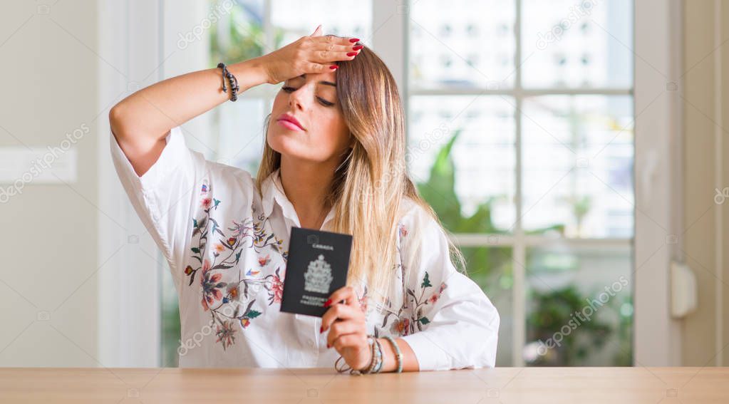 Young woman at home holding a passport of Canada stressed with hand on head, shocked with shame and surprise face, angry and frustrated. Fear and upset for mistake.