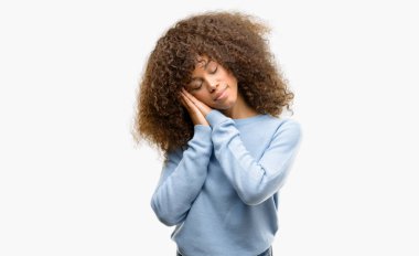 Uyku yorgun hayal ve eller ile birlikte kapalı gözlerle gülümseyerek poz bir kazak giyen Afrikalı-Amerikalı kadın.