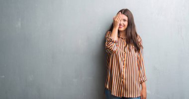 Grunge gri duvar kaplama el yüz ve sürpriz duygu kendinden emin gülümseme ile tek gözlü genç esmer kadın.