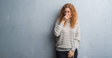 Bir şey pis ve iğrenç kokulu gri grunge duvar, dayanılmaz koku, holding nefes burun parmaklar ile genç Kızıl saçlı kadın. Kötü kokuyor kavramı.