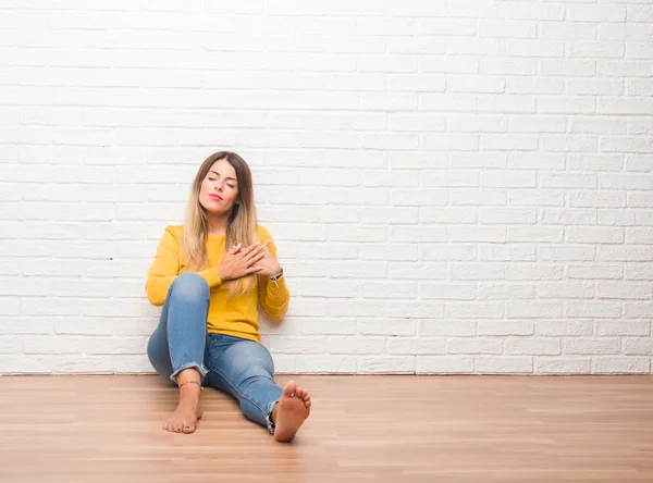 Jonge Volwassen Vrouw Zittend Vloer Witte Bakstenen Muur Glimlachend Met — Stockfoto