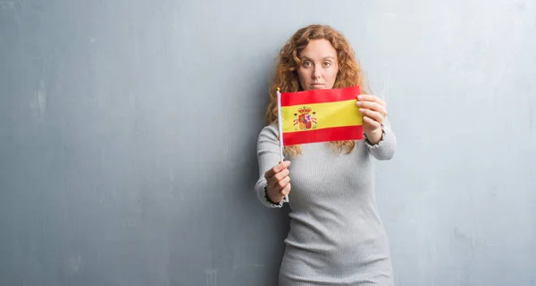 Молодих Redhead Жінка Над Сірий Гранж Стіни Тримає Прапор Іспанії — стокове фото