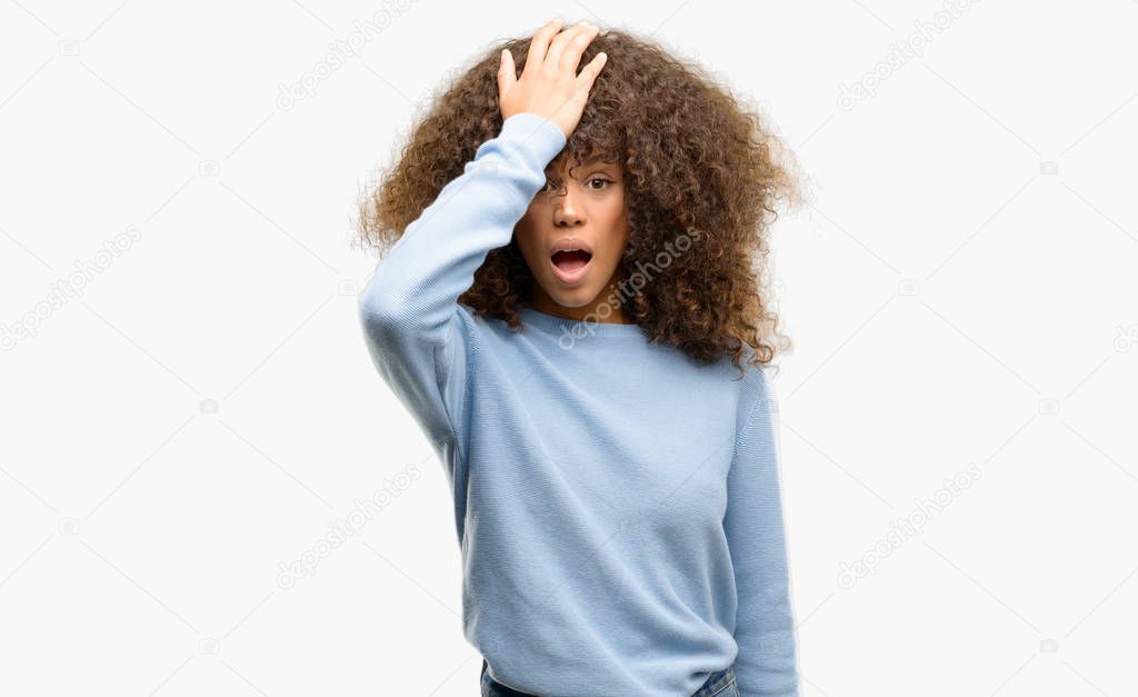 African american woman wearing a sweater surprised with hand on head for mistake, remember error. Forgot, bad memory concept.