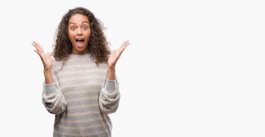 Giyen güzel genç İspanyol kadın kazak kutluyor deli çizgili ve çığlık kaldırdı ve açık gözleri hayret silah ile başarı için heyecanlı. Kazanan kavramı