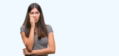 Young beautiful hispanic woman looking stressed and nervous with hands on mouth biting nails. Anxiety problem. clipart