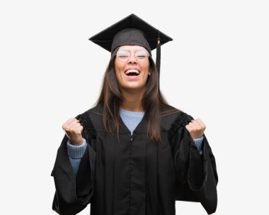 Giyen genç İspanyol kadın kap mezun oldu ve Tekdüzen kutluyor şaşırttı ve başarı için kaldırdı kollarını açarak hayret ve gözleri açık. Kazanan kavramı.