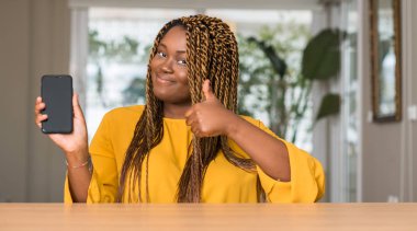 Ok işareti, başparmak ile parmak, mükemmel işareti yapıyor kocaman bir gülümseme ile Smartphone mutlu kullanan Afrikalı-Amerikalı kadın