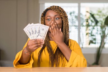 Afrikalı-Amerikalı kadın holding dolar el hata, korku, sessizlik içinde gizli kavramı korkmuş ifade için utanç ile şok ile ağız kapak