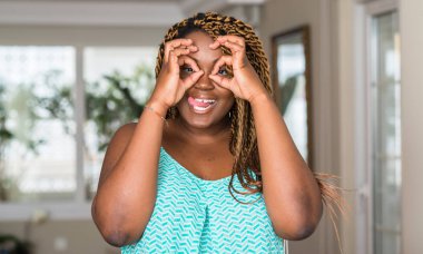 Afrikalı-Amerikalı kadın evde dilini, parmaklarının arasından baktığını yapışmasını dürbün gibi ok jest yapıyor. Deli ifade.