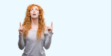 Genç Kızıl saçlı kadın hayrete ve yukarıya bakıp parmakları ile işaret şaşırttı ve silah kaldırdı.