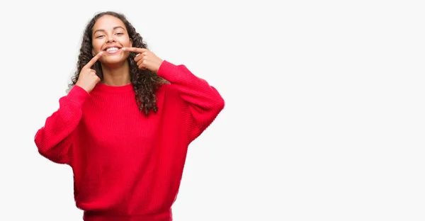 若いヒスパニックの女性は自信を示すと指歯と口を指して笑って赤いセーターを着ています 健康の概念 — ストック写真
