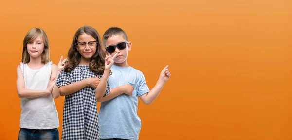 소년과 소녀의 오렌지 배경에 손가락 측면을 가리키는 — 스톡 사진