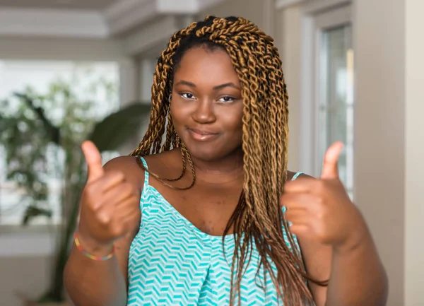 アフリカ系アメリカ人の女性の手で肯定的なジェスチャーを行うホーム成功アットマークは親指を笑顔と幸せです 勝者ジェスチャー晴れやかな表情でカメラを見てください — ストック写真