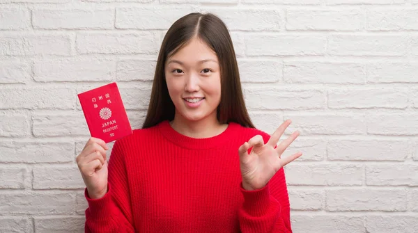 中国年轻女子墙上持有日本护照做 标志与手指 优秀的标志 — 图库照片