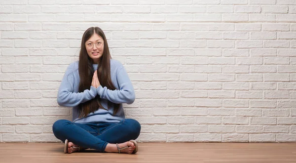 年轻的中国女人坐在砖墙上 用双手祈祷 满怀希望地在脸上表情非常激动和担忧 请求宽恕 宗教概念 — 图库照片