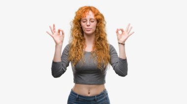 Genç Kızıl saçlı kadın dinlenmek ve gülümseyen gözlerle kapalı parmak jestle meditasyon yapıyor. Yoga kavramı.