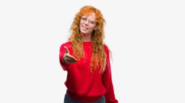 Kırmızı kazaklı tebrik ve konuksever dost sunan karşılıklı gülümseyen giyen genç Kızıl saçlı kadın. Başarılı iş.