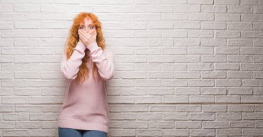 Tuğla duvar eller için hata ile ağız kapsayan şok üzerinde duran genç Kızıl saçlı kadın. Gizli kavramı.