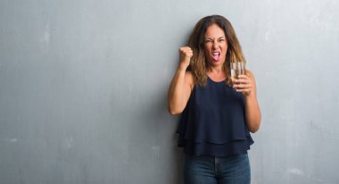 Orta yaş İspanyol kadın içme su rahatsız ve öfke, çılgın ve yükseltilmiş el, öfke kavramı ile diye bağıran ile sinirli bağırarak