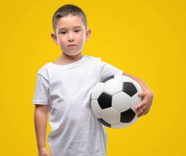 Futbol topu ile acımak yüz ciddi düşünme emin bir ifade ile oynayan koyu saçlı küçük çocuk